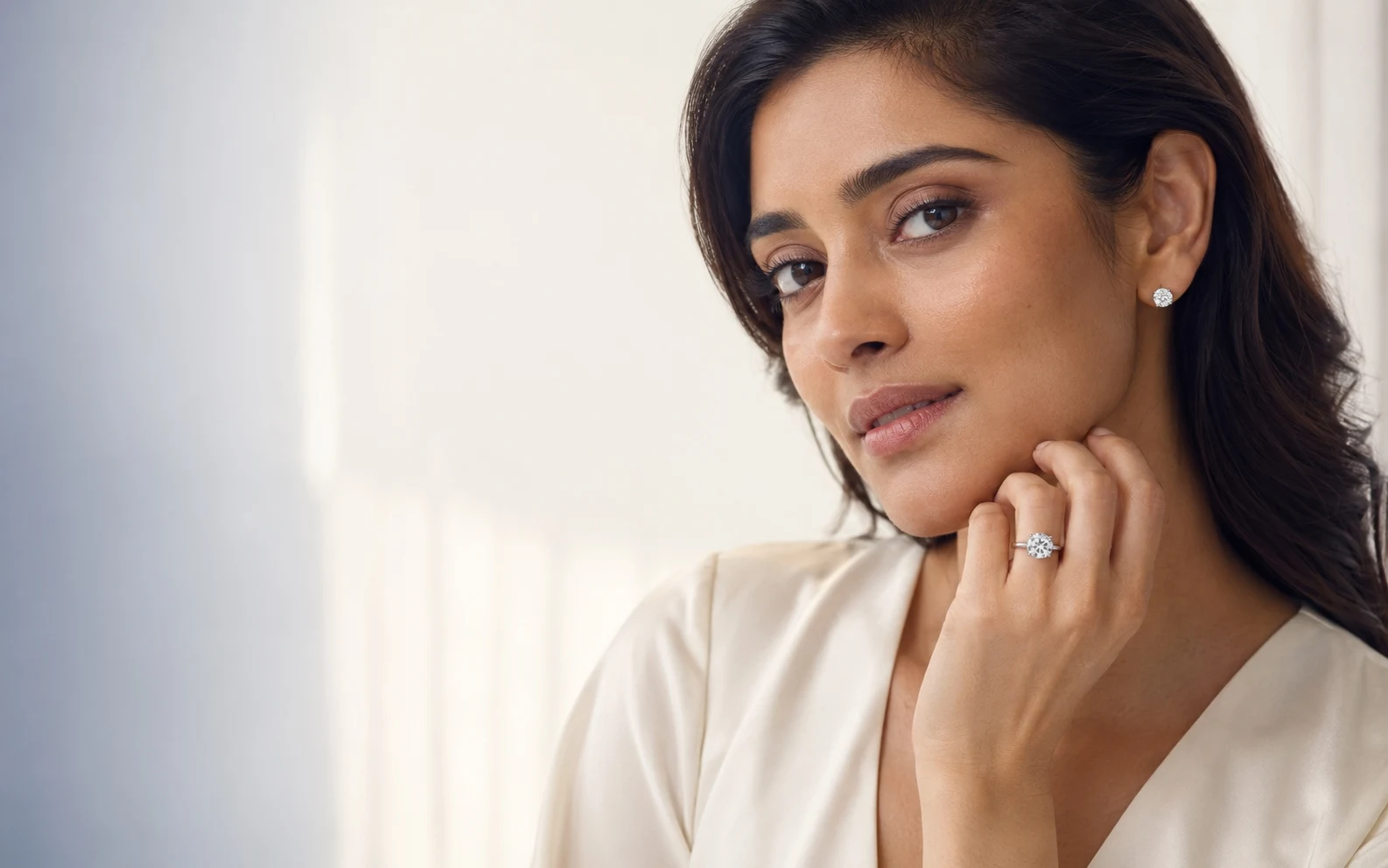 Woman wearing a platinum engagement ring and platinum diamond stud earrings